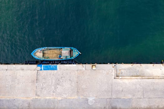 Aerial top view by Drone of the moored small fishing boat at the quay. 