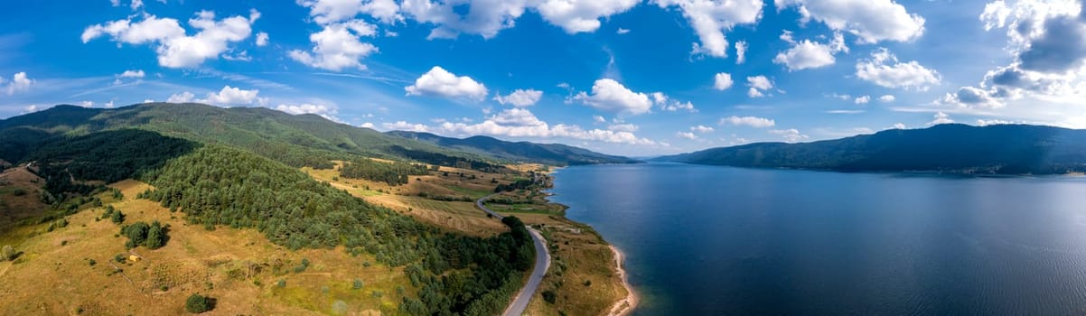 Spectacular aerial view from a drone to a lake , hills, and a road between.