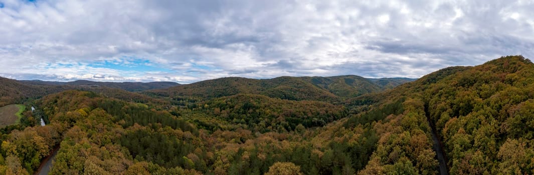 Panoramic Aerial View view of mountain hills. Hilltops covered with autumn forest.