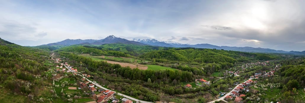 Amazing panoramic view of the countryside, mountain with snow peaks and green hills.