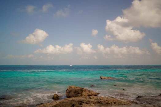 The coastline of the Caribbean Sea with white sand and rocks in Cancun.