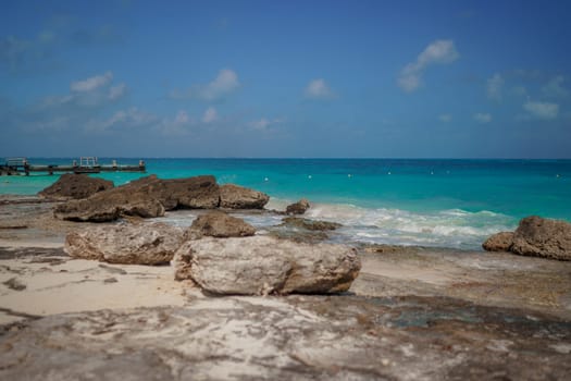 The coastline of the Caribbean Sea with white sand and rocks in Cancun.