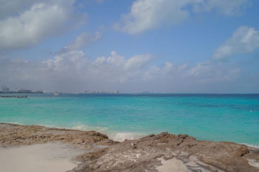 The coastline of the Caribbean Sea with white sand and rocks in Cancun.