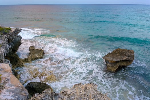 The coastline of the Caribbean Sea with white sand and rocks in Cancun.