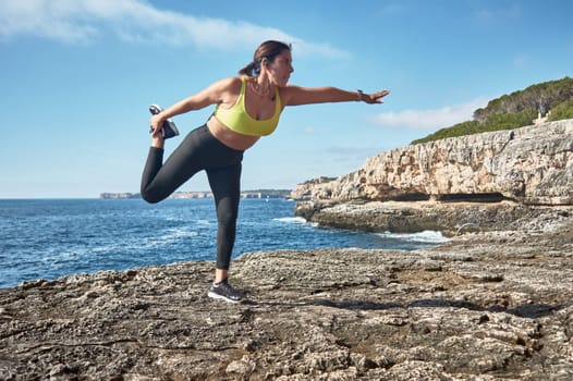 Latin woman, middle-aged, wearing sportswear, training, doing physical exercises, plank, sit-ups, climber's step, burning calories, keeping fit, outdoors by the sea, wearing headphones, smart watch