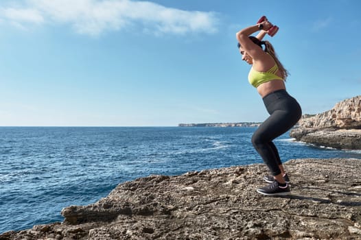 Latin woman, middle-aged, wearing sportswear, training, doing physical exercises, plank, sit-ups, climber's step, burning calories, keeping fit, outdoors by the sea, wearing headphones, smart watch,