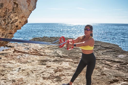 Latin woman, middle-aged, wearing sportswear, training, doing physical exercises, plank, sit-ups, climber's step, burning calories, keeping fit, outdoors by the sea, wearing headphones, smart watch,