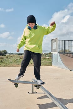 young, teenager, skateboarding, jumping, on the rink, wearing headphones, green sweatshirt, black hat, swinging