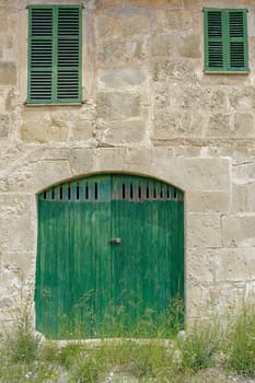 facade of an old farm. Door and windows of natural wood texture, stone walls of Mares, typical natural of Mallorca, rural house for agritourism, different windows, country house.