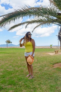 portrait of a latin woman smiling, having fun, on vacation in mallorca posing on a warm spring summer day, under a palm tree, hollidays concept,