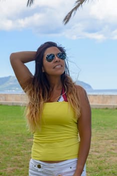 portrait of a latin woman smiling, having fun, on vacation in mallorca posing on a warm spring summer day, under a palm tree, hollidays concept,