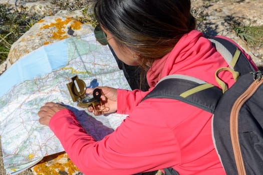 Young hikers sitting on the ground looking at an old map with a compass. Hiking couple in nature