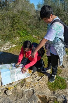Young hiker mother and son with backpacks camping in the woods, looking at an old map with a compass. hiking in nature,