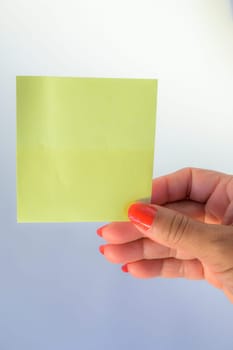 Woman's hand with painted nails holding blank letter paper on pure white background.