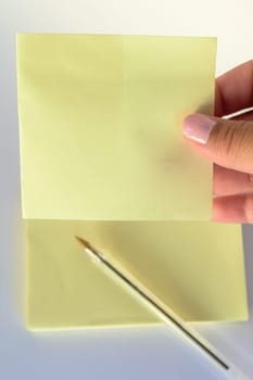 Woman's hand with painted nails holding blank letter paper on pure white background.