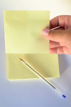 Woman's hand with painted nails holding blank letter paper on pure white background.