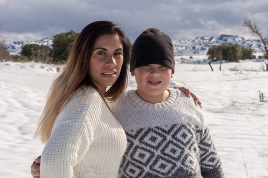 portrait of mother and child looking at camera in snowy field,