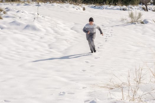 child running in the snow on a sunny day,