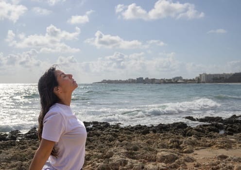 Relaxed woman breathing fresh air on the rocks by the Mediterranean Sea,