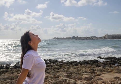 Relaxed woman breathing fresh air on the rocks by the Mediterranean Sea,