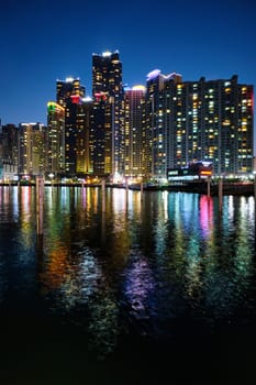 Busan Marina city skyscrapers illluminated in night with reflection in water, South Korea