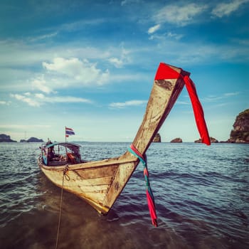 Vintage retro hipster style travel image of Thai Long tail boat on sunset, Krabi, Thailand