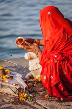 MAHESHWAR, INDIA - APRIL 26: Indian woman performs morning pooja on sacred river Narmada ghats on April 26, 2011 in Maheshwar, Madhya Pradesh, India. To Hindus Narmada is one of 5 holy rivers of India