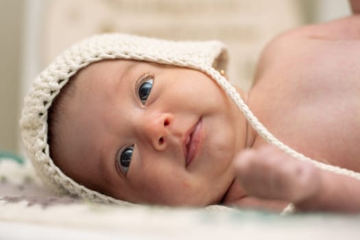 Baby with two months of life in his crib with a wool cap.