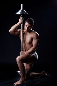 Muscular young athlete posing looking at camera, isolated on black