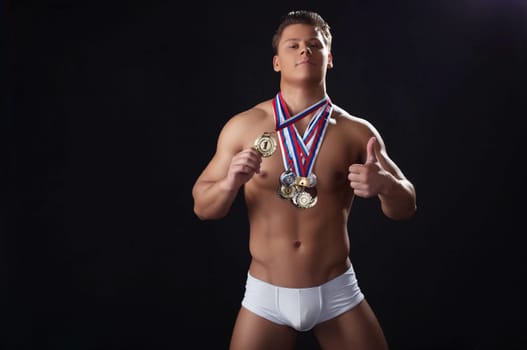 Attractive strong champion posing with awards, isolated on black