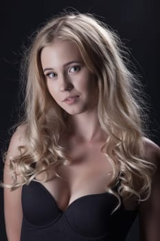 Portrait of charming curly blonde posing in studio, close-up