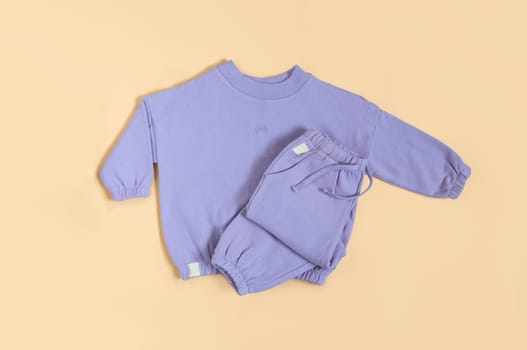 Stylish lilac children's spring, autumn sport costume. Soft touch, warm joggers and sweatshirt. Fashion kids outfit for spring, autumn and winter. Flat lay, top view