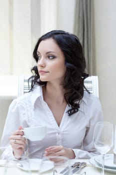 Portrait of beautiful young brunette drinking coffee