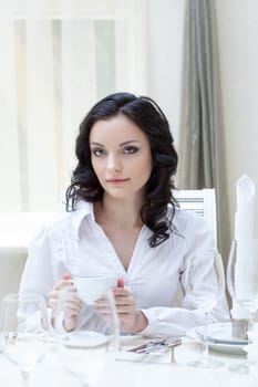 Portrait of attractive brunette sitting at table, close-up