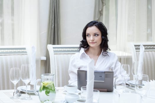 Beautiful slim girl posing with laptop in restaurant