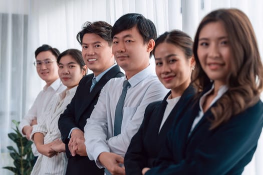 Cohesive group of businesspeople standing in row, holding hand in line together after meeting to promote harmony in workplace. Asian office workers strong teamwork and unity concept.