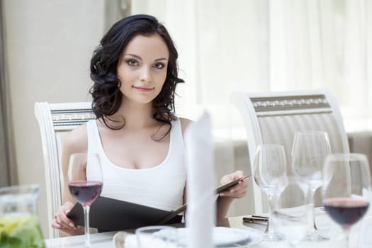 Curvy slender brunette sitting at restaurant table, close-up