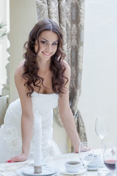 Charming young bride posing near banquet table, close-up