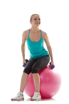 Pretty young athlete posing with dumbbells and ball, isolated on white