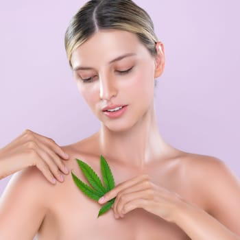 Alluring beautiful woman model portrait holding green leaf as concept for cannabis skincare cosmetic product for perfect skin freshness treatment in isolated pink background.