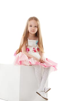 Image of charming fashionista sits on cube in studio, close-up