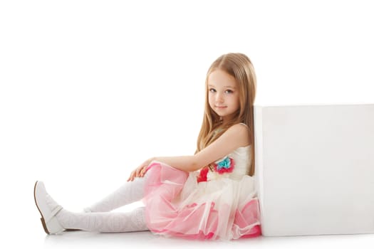 Adorable little girl posing leaning on cube, close-up