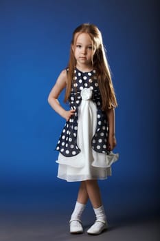Image of cute girl posing in blue polka dot dress, on blue background