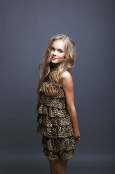 Cute smiling girl posing in fashionable dress, on gray background