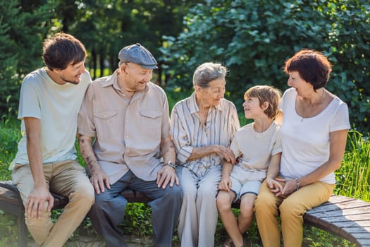 Four generations of family spend time together in the park. Elderly couple. Senior husband and wife holding hands and bonding with true emotions.