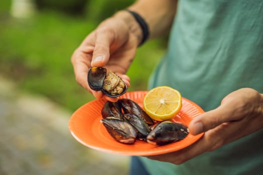 Heap of mussels in shells stuffed with rice. Man is going to eat midye traditional Turkish food. Istanbul, Turkey.