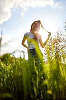 silhouette of a woman standing in a field illuminated from the back straightening her hair. High quality photo