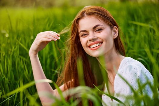 happy smiling redhead woman resting sitting in tall grass. High quality photo