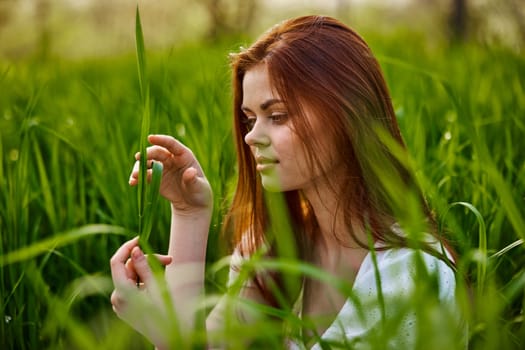 pensive woman with red hair sits in tall grass. High quality photo