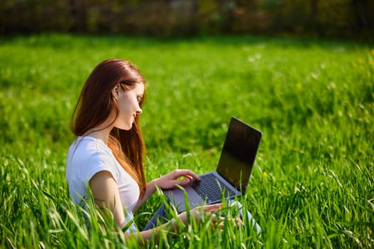 Portrait of beautiful young woman on nature with laptop. High quality photo